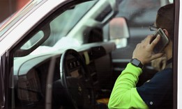A motorist holds a phone while stopped at a traffic light while driving.