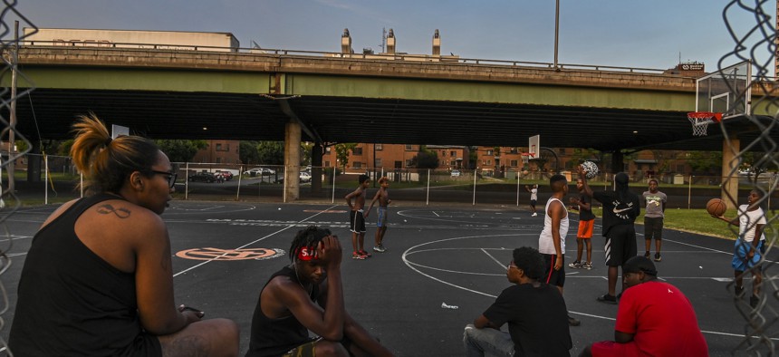 Kids play basketball at Wilson Park near where highway I-81 slices through a public housing complex on the south side of Syracuse, New York, in 2019. More than 50 years ago, construction of the highway displaced longtime residents and split predominantly Black communities, contributing to increases in poverty and pollution. 