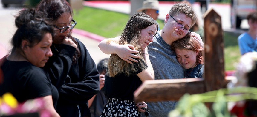 enni Seeley, Dakota Britvich, and Abbi Boyd hug as they visit a memorial set up near the scene of a mass shooting at the Allen Premium Outlets mall on May 8, 2023 in Allen, Texas. Eight people were killed and seven wounded in the Saturday attack in which the gunman was killed by police, according to published reports. 