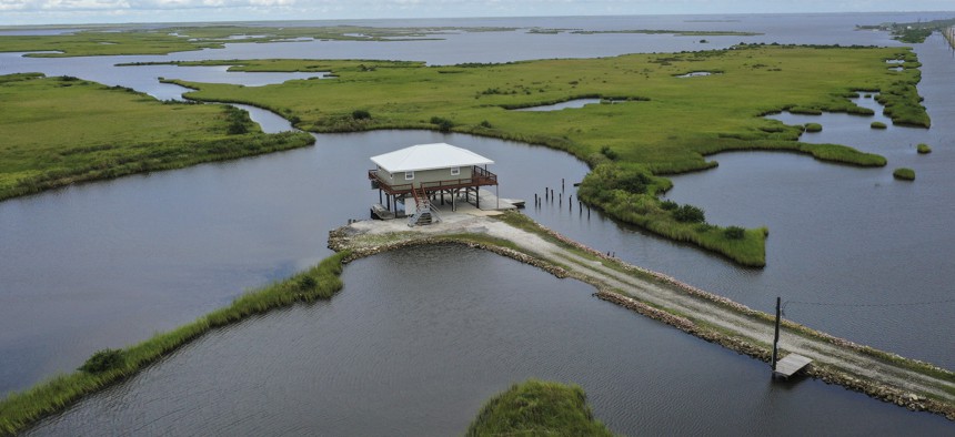 A home on stilts sits amidst coastal waters and marshlands along Louisiana Highway 1 in Grand Isle, Louisiana.