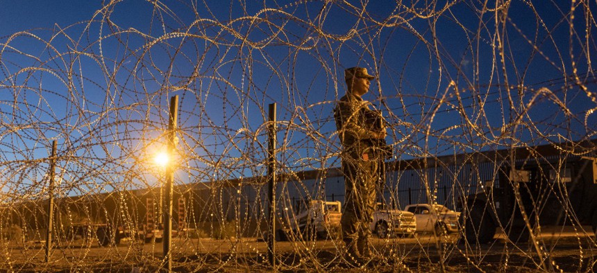 A Texas National Guard soldier stands vigil at a makeshift migrant camp near the U.S.-Mexico border fence in El Paso, Texas.