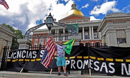 A man holds a Brazilian and U.S. flag to celebrate the passage of a 2022 Massachusetts law that would allow people in Massachusetts with out legal immigration status to get a drivers license.