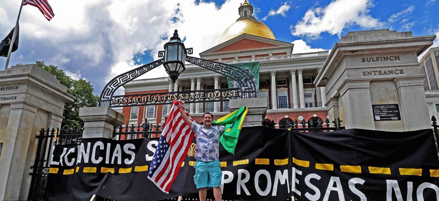 A man holds a Brazilian and U.S. flag to celebrate the passage of a 2022 Massachusetts law that would allow people in Massachusetts with out legal immigration status to get a drivers license.