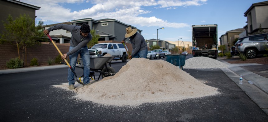 Workers from an artificial turf company load sandy gravel into a wheelbarrow to replace natural grass with artificial landscape in Las Vegas last summer. 