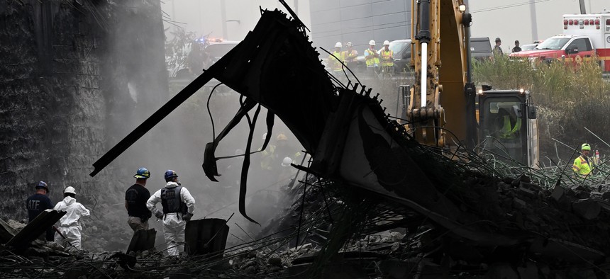 Workers inspect and clear debris from a section of the bridge that collapsed on Interstate 95 after an oil tanker explosion on June 12 in Philadelphia.