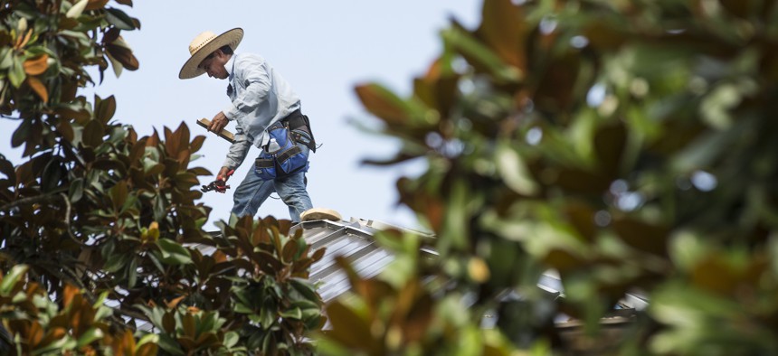 A roofer wears a wide brimmed hat as he braves the Texas heat in 2021.  Texas has enacted a law that nullifies city rules requiring water and shade breaks for laborers.