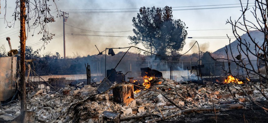 A fire continues to smolder inside the remains of a home in Perris, California, on June 27, 2023.