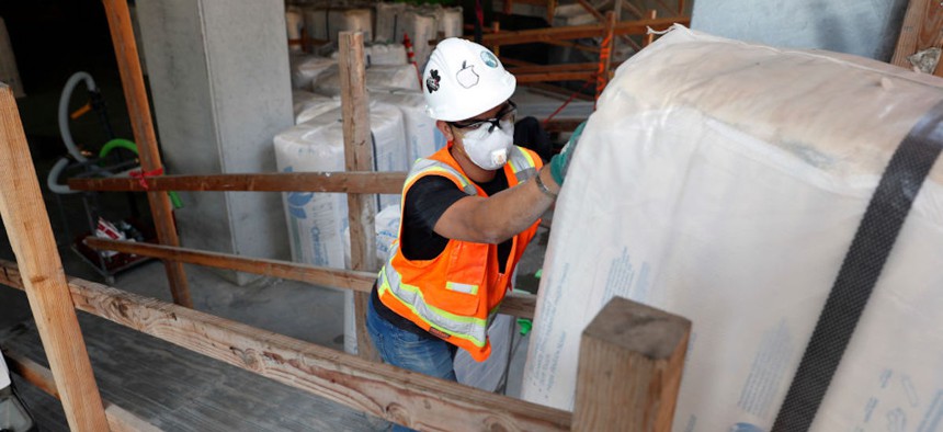 A construction worker pushes a bale of insulation onto an elevator platform at the construction site of a residential building in Oakland, California, on Wednesday, July 17, 2019. 