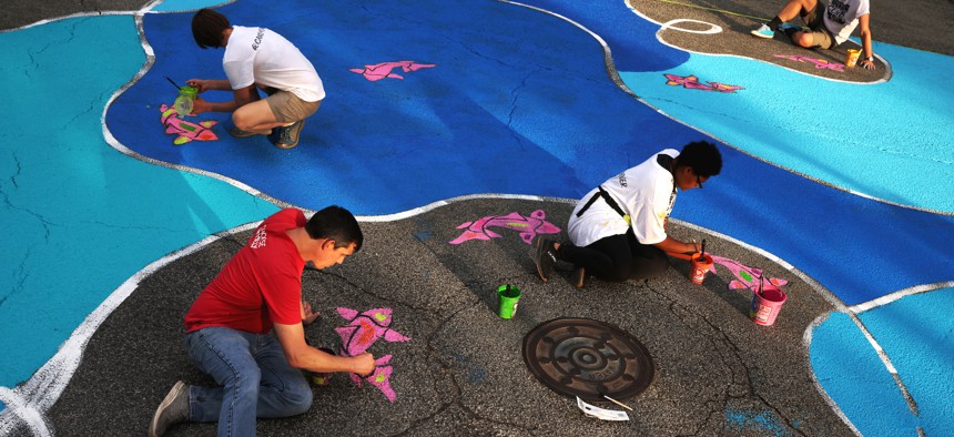 Volunteers paint an intersection mural in Durham, leading to fewer conflicts between drivers and pedestrians and a greater sense of safety for people crossing the street.