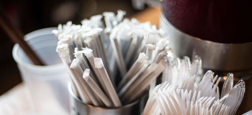 Plastic straws wrapped in paper and plastic forks are seen at a food hall in Washington D.C. on June 20, 2019. The city banned plastic straws in 2019 in an effort to reduce waste and environmental harm.