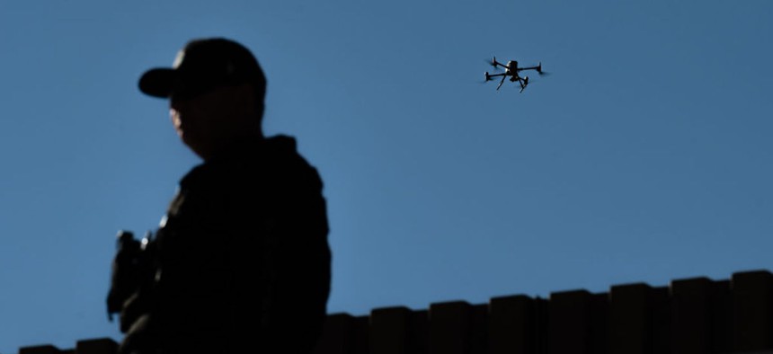 A drone hovers over members of law enforcement stand watch over a gathering on a sidewalk in protest of the election process in front of the Maricopa County Tabulation and Election Center on Nov. 14, 2022, in Phoenix, Arizona.
