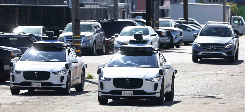 Waymo cars drive down a San Francisco street in March.