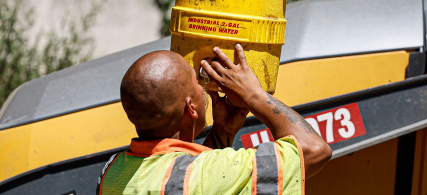 Los Angeles County crew member Jonathan Lainez hydrates as he works to repave a section of East Altadena Drives as temperatures reach 100 degrees and above.