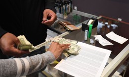 Customers pay cash for their purchase at the Green Pearl Organics dispensary on the first day of legal recreational marijuana sales on Jan. 1, 2018 in Desert Hot Springs, California.