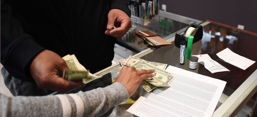 Customers pay cash for their purchase at the Green Pearl Organics dispensary on the first day of legal recreational marijuana sales on Jan. 1, 2018 in Desert Hot Springs, California.