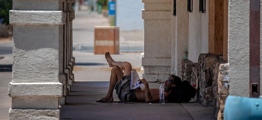 Dray Taijer, 59, who is homeless for one year, escapes scorching heat in the shade of a vacant business building on Thursday, July 20, 2023 along main thoroughfare Hobsonway in Blythe, CA.