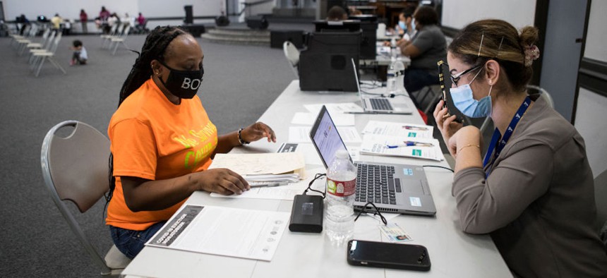Danielle Hampton, left, helps a resident apply for the Houston-Harris County Emergency Rental Assistance Program at Harvest Time Church on June 30, 2021, in Houston, Texas. 