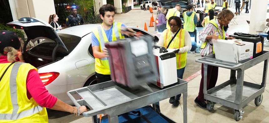 Election volunteers and employees for Harris County, Texas, retrieve voting poll items from election judges cars at NRG Stadium on Tuesday, Nov. 7, 2023, in Houston. (