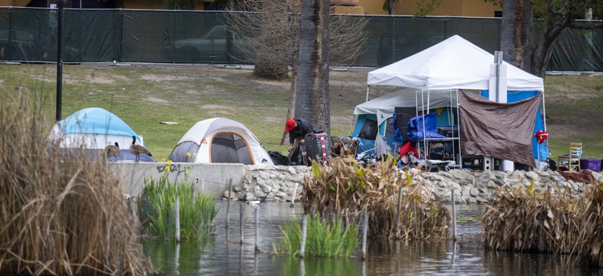 People experiencing homelessness pack up their belongings in a Los Angeles park.