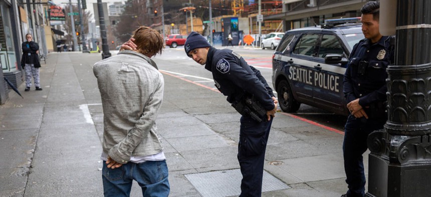 Police officers check on a man who said he has been smoking fentanyl in downtown Seattle on March 14, 2022, in Seattle, Washington. 