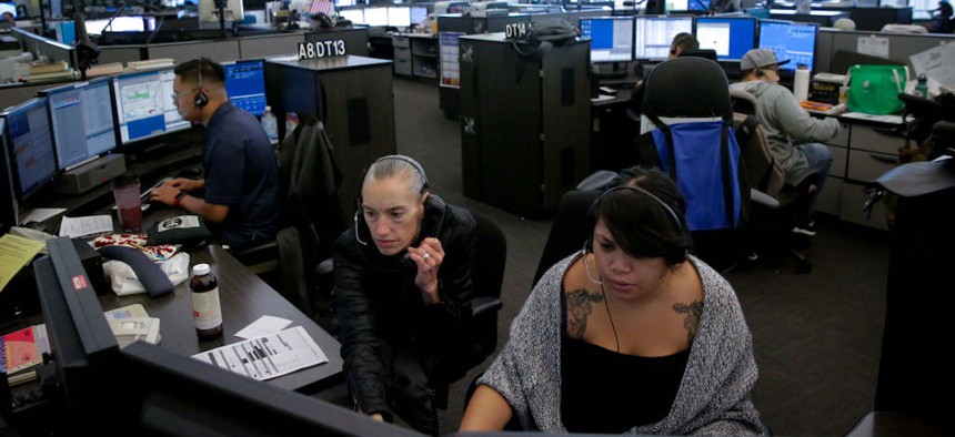 Dispatchers Justin Wong, (left) and Joan Vallarino, (center) with Kim Delara, a dispatch trainee at the San Francisco 911 Emergency Call Center on July 31, 2017, in San Francisco.