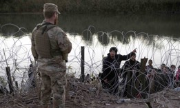  A migrant from Venezuela asks a Texas National guardsman directions to a processing center after crossing from Mexico into the United States in December in Eagle Pass, Texas. A surge of migrants, as many as 12,000 per day, crossing the U.S. southern border has overwhelmed U.S. immigration authorities. 