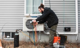 An HVAC technician installs a heat pump in Maine in 2023.