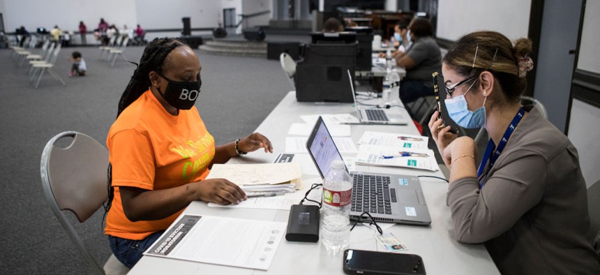 Danielle Hampton, left, works with Asia Alkakie, of the YMCA, as she applies for help through the Houston-Harris County Emergency Rental Assistance Program at Harvest Time Church on June 30, 2021, in Houston, Texas. 