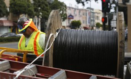 Electrical line worker walks past a spool of fiber optic cable after laying the cable earlier in the day.