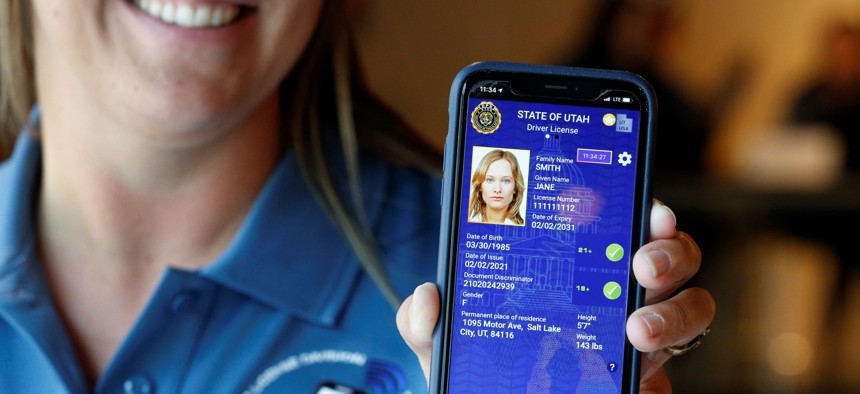 A Utah Department of Motor Vehicle employee shows a sample of a digital driver's license on a mobile phone in 2021.