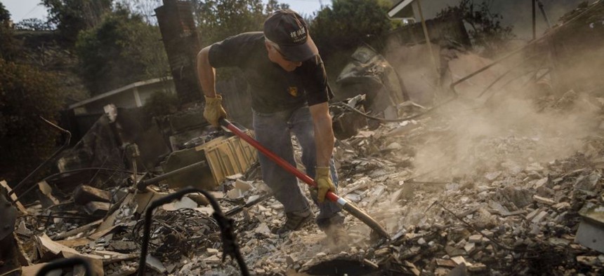 Jeff Lipscomb sorts through the debris looking for items to recover after his home was destroyed in a brush fire on December 6, 2017 in Ventura, California. 