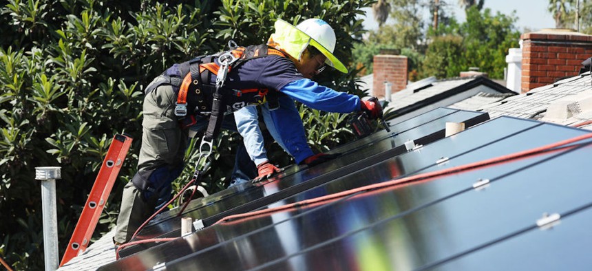 GRID Alternatives employee Tony Chang installs no-cost solar panels on the rooftop of a low-income household on Oct. 19, 2023, in Pomona, California. 
