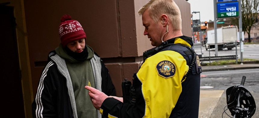 Portland Police officer Eli Arnold issues a citation for drug use and a business card showing a number to call for a health screening and services in order to avoid a $100 fine in downtown Portland, Oregon on January 25, 2024.