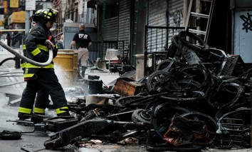 Firefighters work outside a building in Chinatown after four people were killed by a fire in an e-bike repair shop overnight on June 20, 2023, in New York City. 