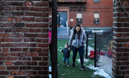 A woman walks with her 20-month-old son through the courtyard of United South End Settlements, a Massachusetts-based organization that supports guaranteed income programs. 