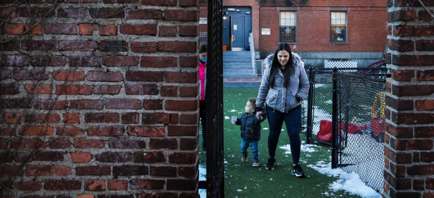 A woman walks with her 20-month-old son through the courtyard of United South End Settlements, a Massachusetts-based organization that supports guaranteed income programs. 