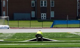 A contractor works to replace artificial turf at Newton South High School in Newton, California, in August 2023. 