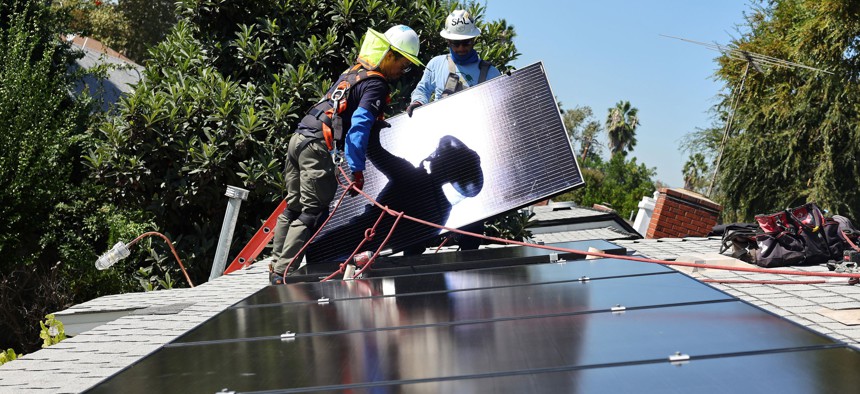 GRID Alternatives employees Tony Chang (L) and Sal Miranda install no-cost solar panels on the rooftop of a low-income household on October 19, 2023 in Pomona, California. 