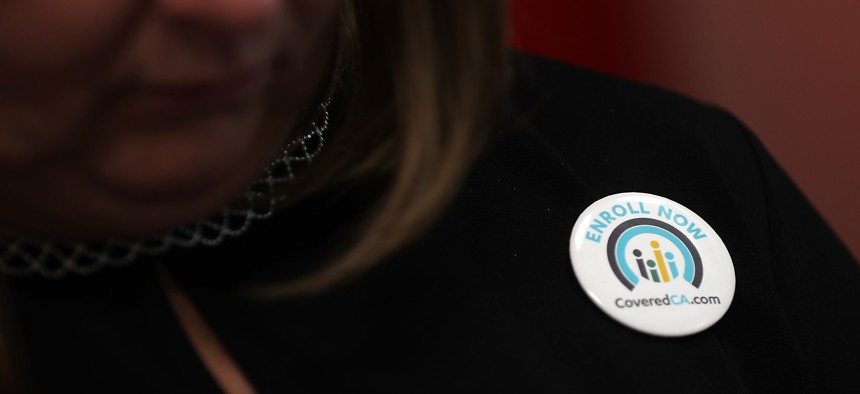 A woman wears a button promoting open enrollment with Covered California, which will use AI to automate some of the enrollment process.