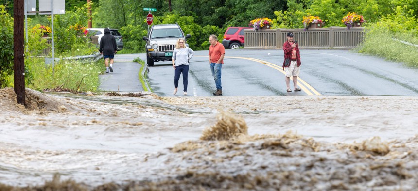 Onlookers check out a flooded road on July 10, 2023 in Chester, Vermont. Torrential rain and flooding has affected millions of people from Vermont south to North Carolina.