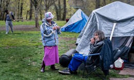 Unhoused senior citizens Kim Morris and Kevin Gevas call a homeless advocate from Mint at Tussing Park in Grants Pass, Oregon in March. The town of Grants Pass is enforcing an anti-camping ordinance, which includes fines for sleeping in any park or public space. The homeless population says it violates their constitutional rights. 