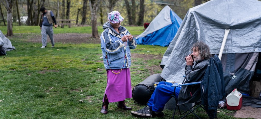 Unhoused senior citizens Kim Morris and Kevin Gevas call a homeless advocate from Mint at Tussing Park in Grants Pass, Oregon in March. The town of Grants Pass is enforcing an anti-camping ordinance, which includes fines for sleeping in any park or public space. The homeless population says it violates their constitutional rights. 
