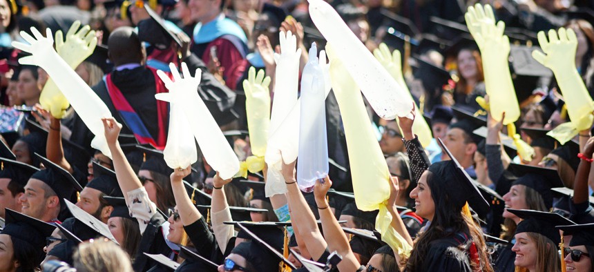 Medical school graduates hold inflated surgical gloves during commencement at the University of Pennsylvania.