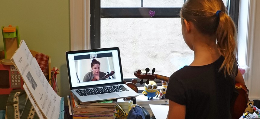 Schoolgirl learning to play a viola using a laptop to watch and listen her music teacher from her bedroom during the Coronavirus lockdown on March 17, 2020 in New York, NY.