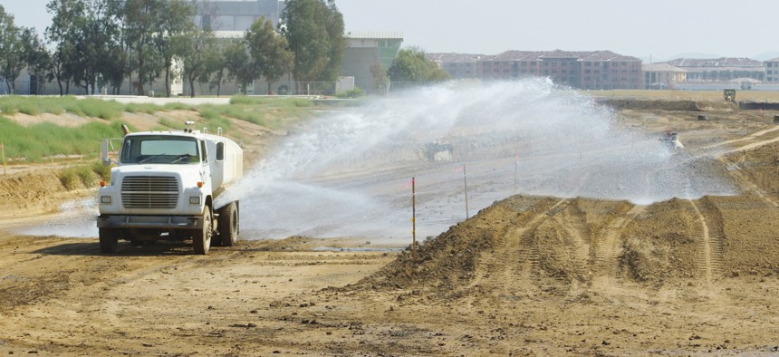 Water truck wetting dirt for dust control and moisture conditioning so it is easier to compact and work. 