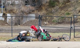 Homeless man laying on the ground with his possessions in Ogden City, Utah.