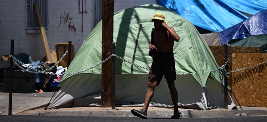 A person walks by a homeless encampment during a record heat wave in Phoenix, Arizona, on July 18, 2023. 