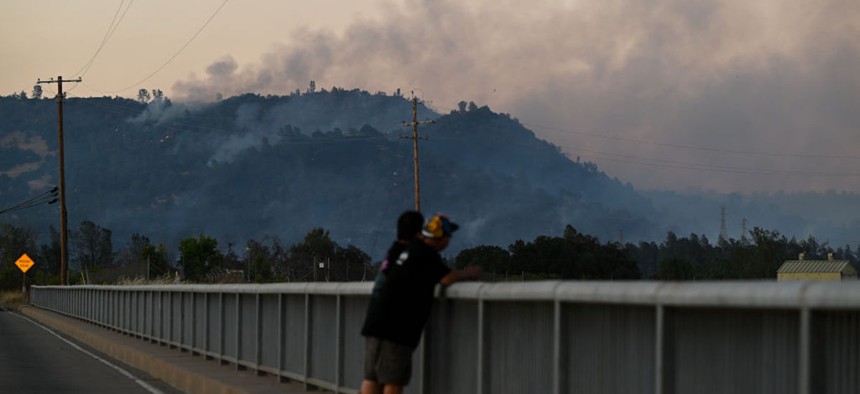 Men watch the Thompson Fire as wildfires continue in Oroville of Butte County in California, on July 2, 2024. 