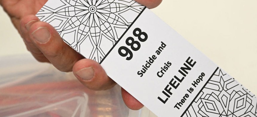 A bookmark for children with the 988 suicide and crisis lifeline emergency telephone number is displayed by Lance Neiberger, a volunteer with the Natrona County Suicide Prevention Task Force, while they speak about mental health and suicide awareness in Casper, Wyoming on August 14, 2022. 