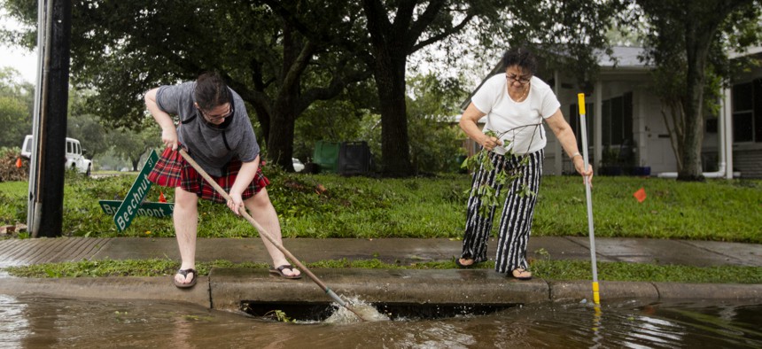 Residents help clear neighborhood drains after Hurricane Beryl made landfall early morning on July 8 in Houston.